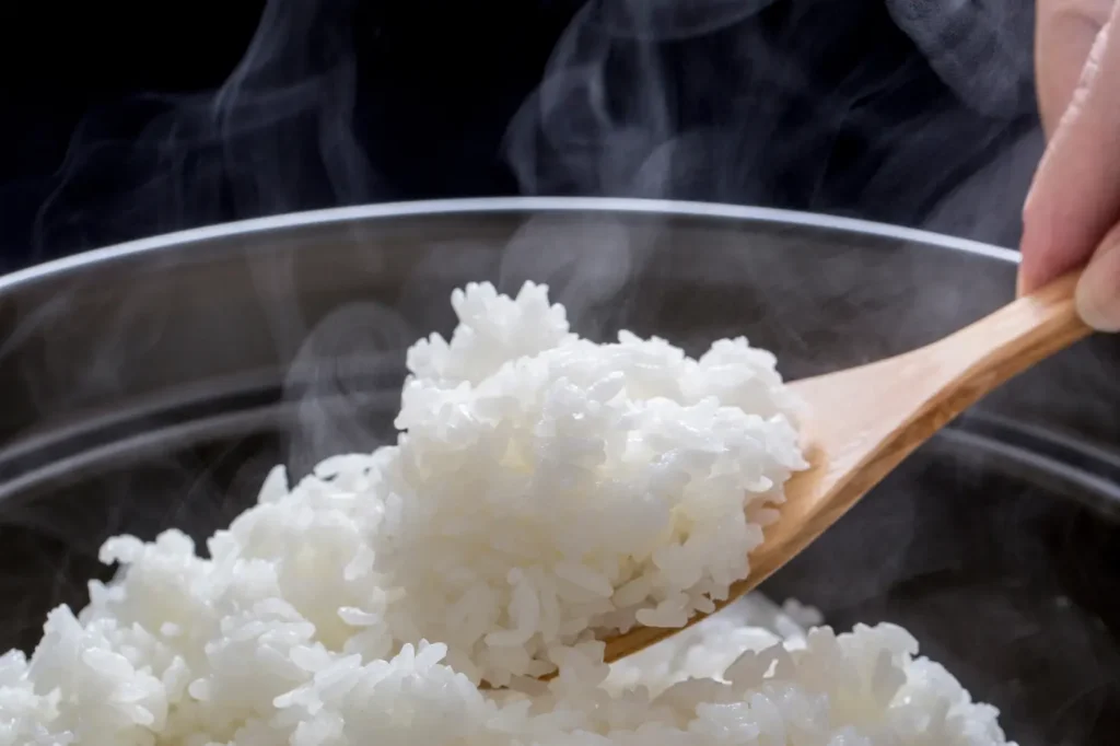 Scooping freshly cooked rice with a rice paddle